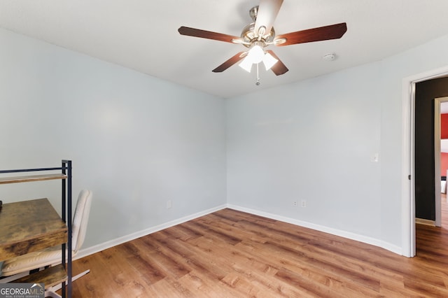 spare room featuring a ceiling fan, light wood-style flooring, and baseboards