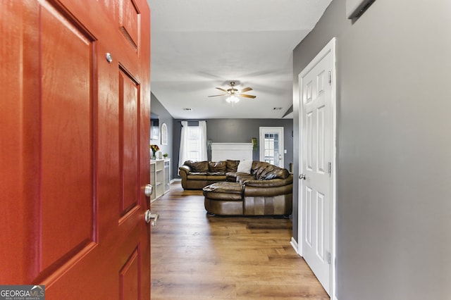 entryway featuring a fireplace, wood finished floors, and a ceiling fan