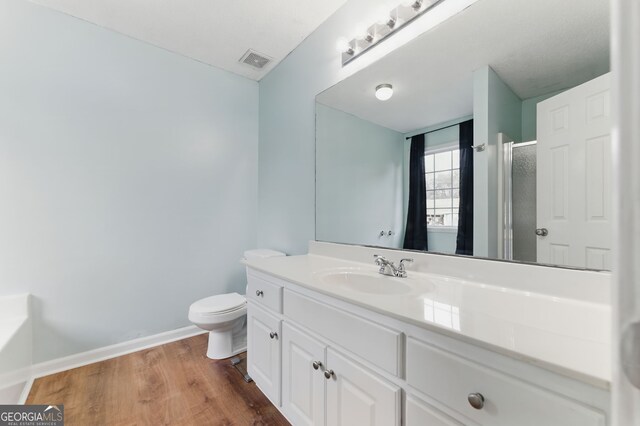 full bath featuring visible vents, an enclosed shower, vanity, wood finished floors, and baseboards