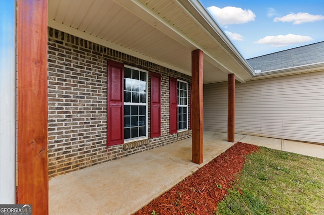 entrance to property featuring roof with shingles and brick siding