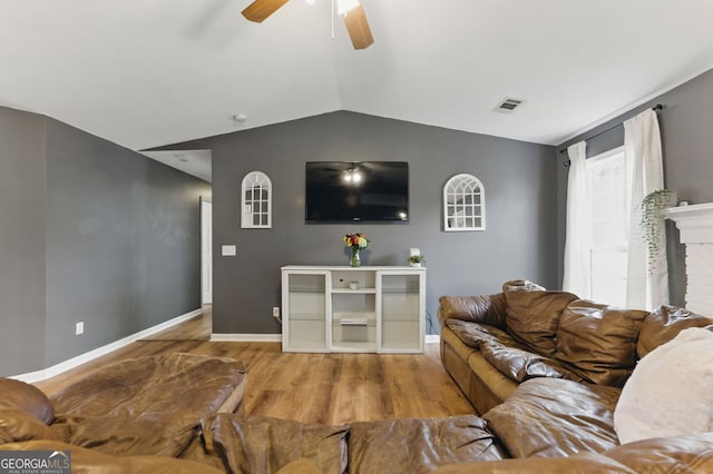 living area featuring visible vents, a ceiling fan, vaulted ceiling, wood finished floors, and baseboards