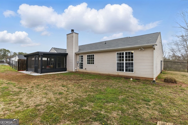 rear view of property with a sunroom, a chimney, fence, and a yard