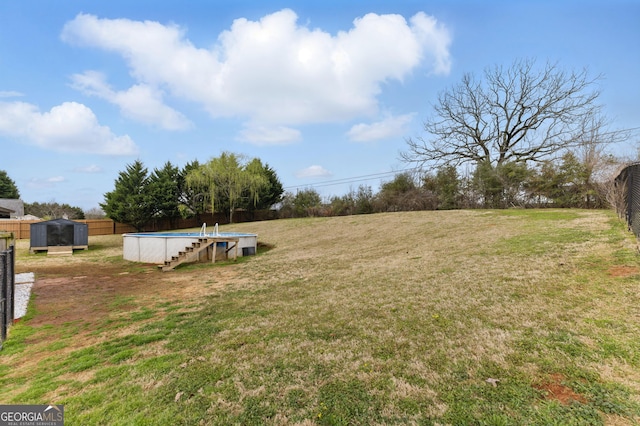 view of yard with fence, an outdoor pool, and an outdoor structure