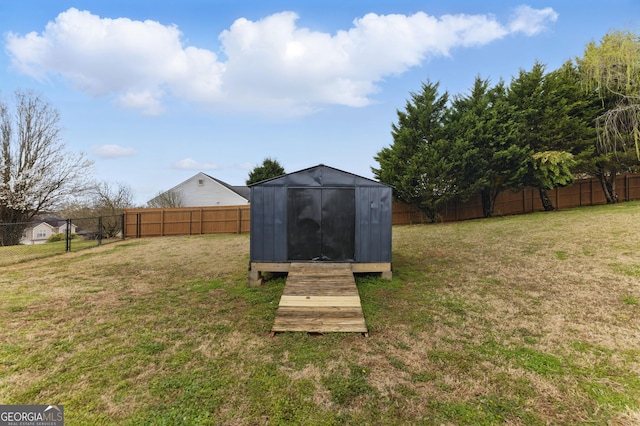 view of yard featuring a storage shed, a fenced backyard, and an outdoor structure