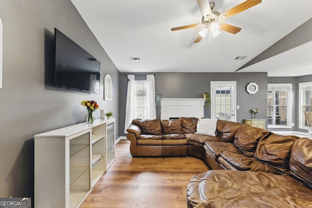 living room featuring lofted ceiling, ceiling fan, visible vents, and wood finished floors