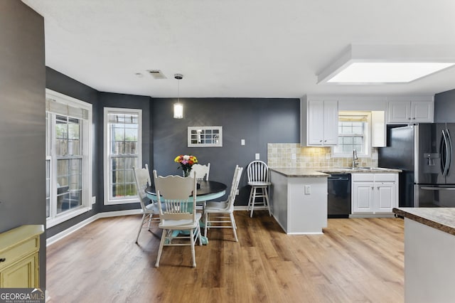 kitchen featuring black dishwasher, light wood finished floors, decorative backsplash, and stainless steel fridge with ice dispenser