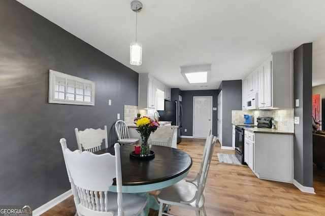 dining space featuring light wood-style flooring and baseboards