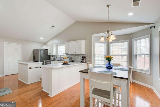 kitchen featuring visible vents, a center island, light wood-style floors, stainless steel fridge, and a sink