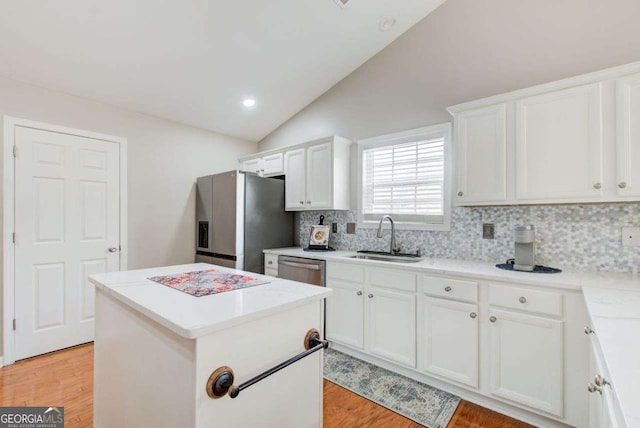 kitchen featuring a center island, vaulted ceiling, light wood-style flooring, appliances with stainless steel finishes, and a sink