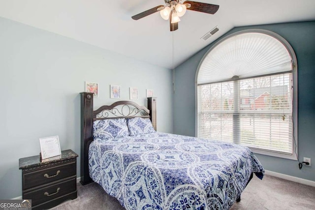 carpeted bedroom featuring a ceiling fan, vaulted ceiling, baseboards, and visible vents