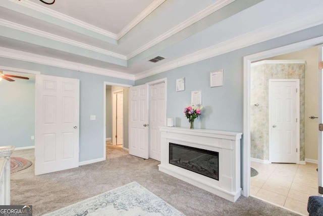 tiled living area with visible vents, crown molding, carpet flooring, a glass covered fireplace, and a ceiling fan