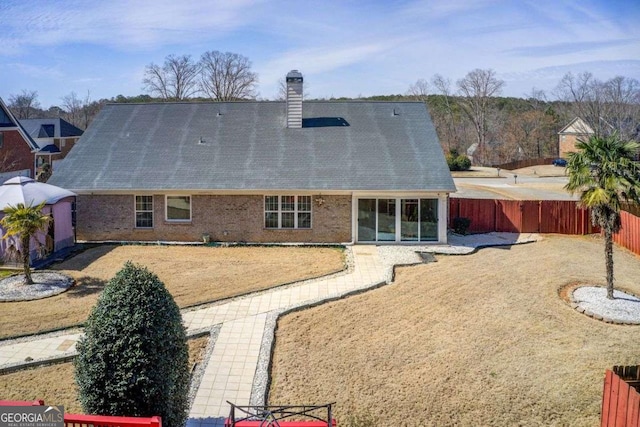 rear view of house featuring a fenced backyard, a shingled roof, a chimney, a patio area, and brick siding