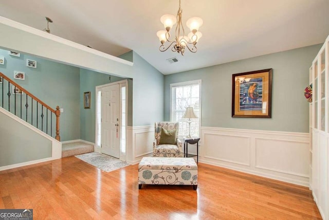 living area featuring a notable chandelier, stairs, visible vents, and wood finished floors