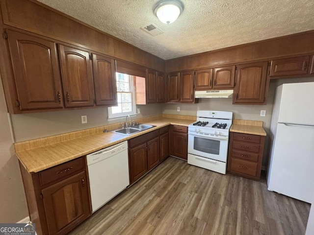 kitchen with light wood finished floors, visible vents, a sink, white appliances, and under cabinet range hood