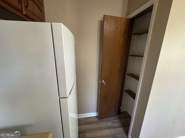 interior space featuring freestanding refrigerator, light wood-style flooring, baseboards, and open shelves