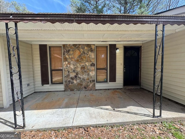 doorway to property with covered porch and stone siding