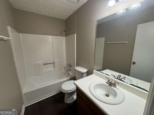 bathroom with wood finished floors, toilet, vanity, shower / tub combination, and a textured ceiling