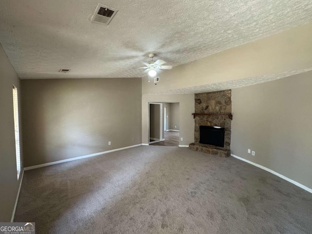 unfurnished living room with carpet, visible vents, ceiling fan, a stone fireplace, and baseboards