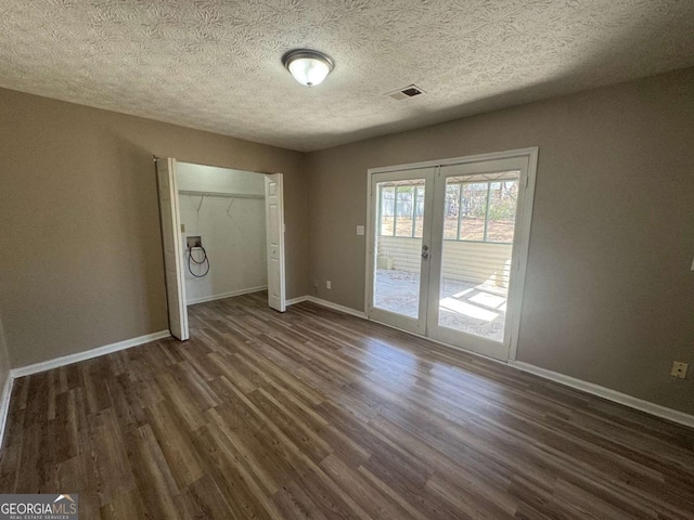 unfurnished bedroom featuring french doors, visible vents, dark wood-type flooring, access to outside, and baseboards