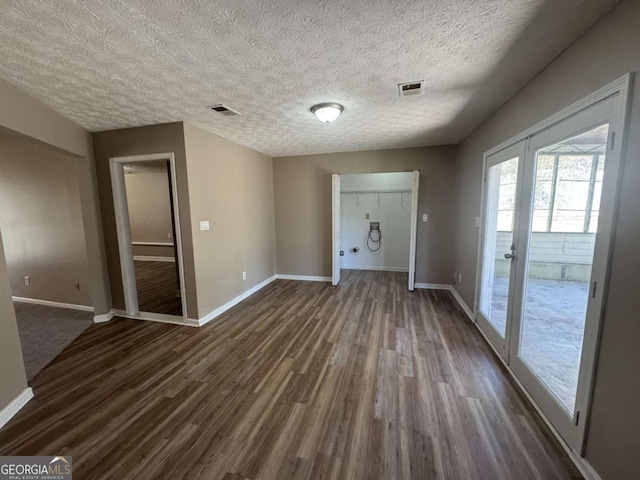 empty room featuring visible vents, dark wood finished floors, and baseboards