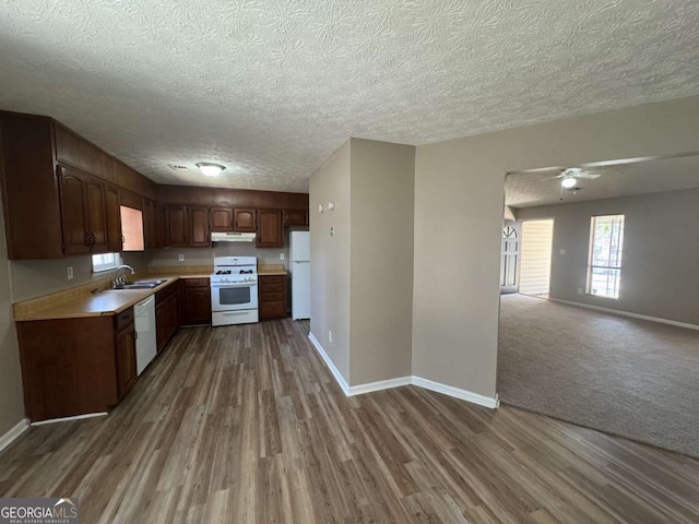 kitchen featuring open floor plan, light countertops, white appliances, and under cabinet range hood