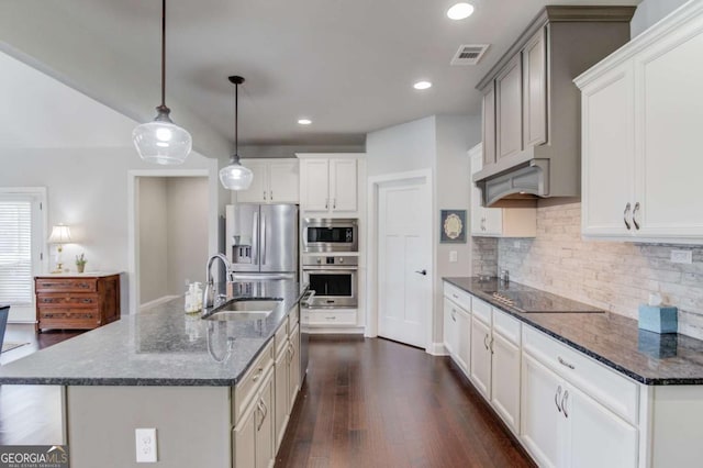 kitchen with stainless steel appliances, a sink, visible vents, decorative backsplash, and dark wood finished floors