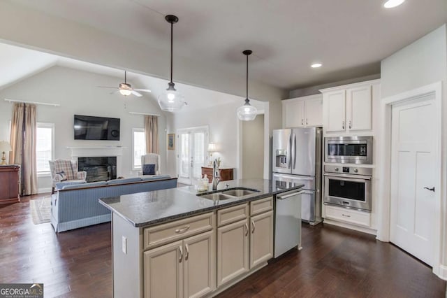 kitchen featuring stainless steel appliances, dark stone counters, a sink, and dark wood-style floors