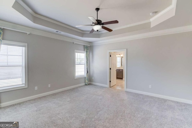 empty room featuring a raised ceiling, visible vents, ornamental molding, light carpet, and baseboards