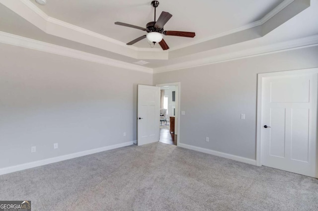 interior space with a ceiling fan, a tray ceiling, crown molding, and baseboards