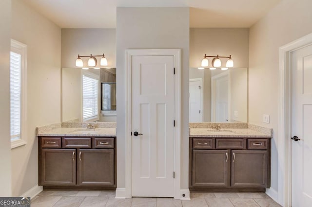 full bathroom with baseboards, two vanities, and a sink