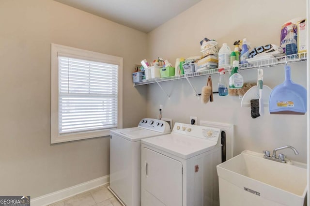 laundry area with laundry area, baseboards, washing machine and dryer, a sink, and light tile patterned flooring