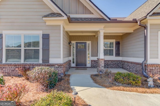 entrance to property with covered porch, brick siding, and board and batten siding