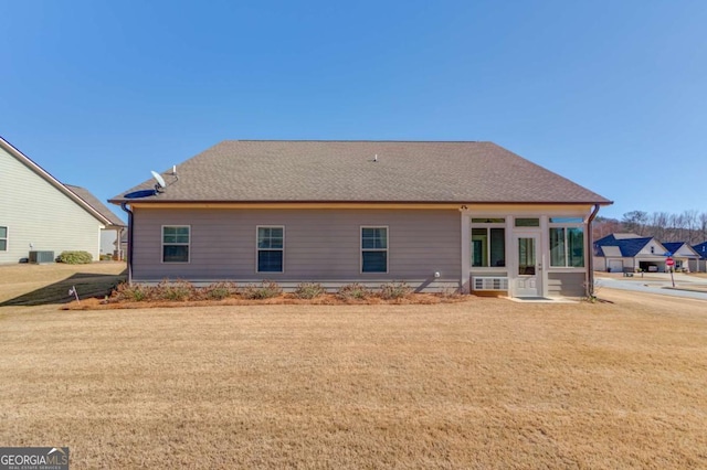 back of property featuring a yard, a shingled roof, and central air condition unit