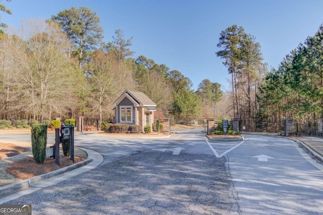 view of street with a gate, a gated entry, and curbs