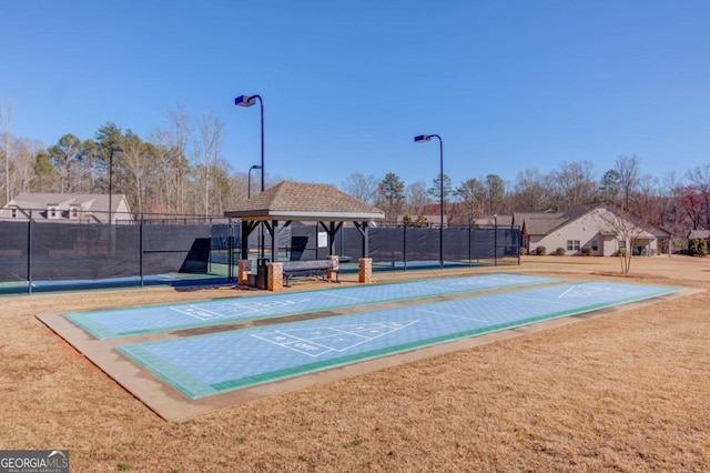 view of home's community with fence, shuffleboard, a lawn, and a gazebo