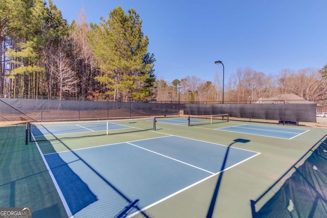 view of tennis court featuring community basketball court and fence