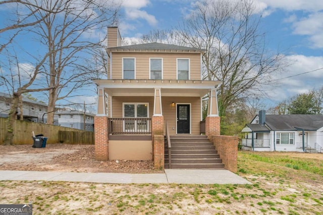 view of front of home featuring covered porch, brick siding, fence, and stairs