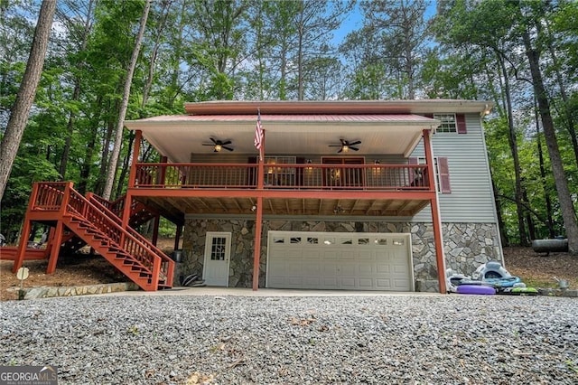 view of front of house with stone siding, a garage, driveway, and ceiling fan