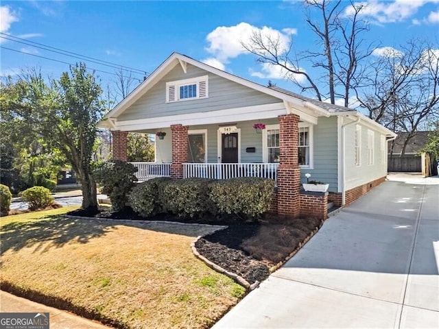 bungalow-style house featuring concrete driveway, a porch, and a front lawn