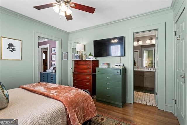 bedroom with ornamental molding, a ceiling fan, ensuite bathroom, and wood finished floors