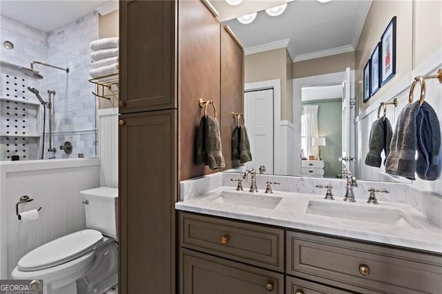 bathroom with toilet, crown molding, a tile shower, and a sink