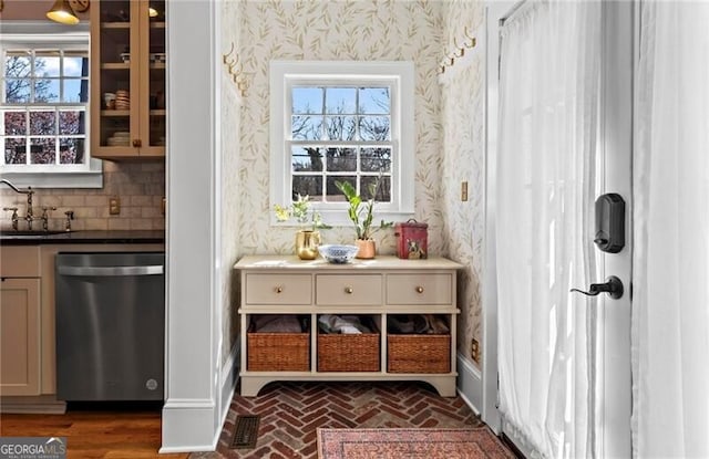 bar featuring brick floor, dishwasher, a sink, and wallpapered walls