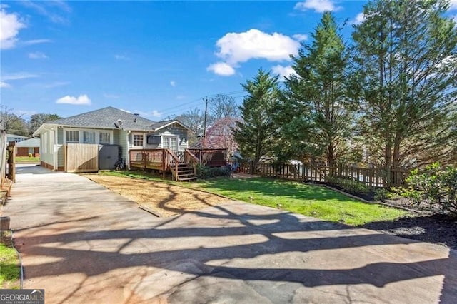 view of front of home featuring a front yard, fence, and a wooden deck