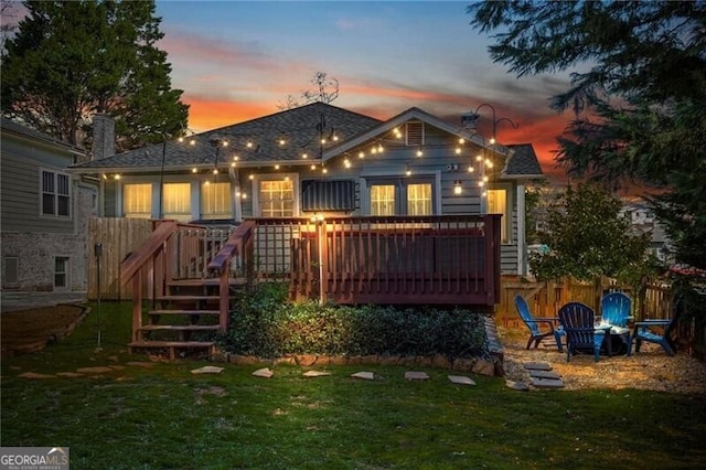 rear view of house featuring an outdoor fire pit, a yard, and a wooden deck