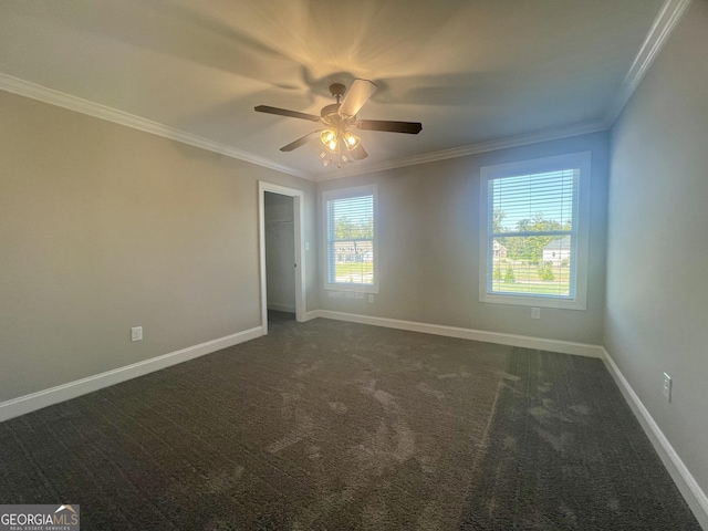 empty room with ceiling fan, ornamental molding, dark carpet, and baseboards