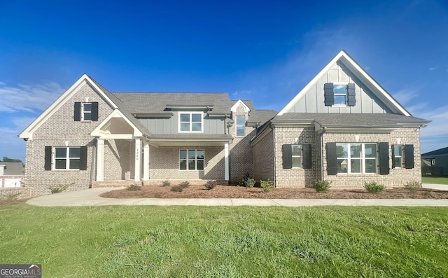 craftsman-style home with board and batten siding, brick siding, and a front lawn