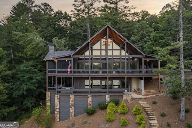 rear view of house with a sunroom, a chimney, and stone siding