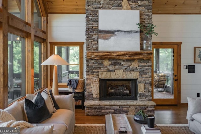 living area featuring a stone fireplace, wooden ceiling, wooden walls, beam ceiling, and wood-type flooring