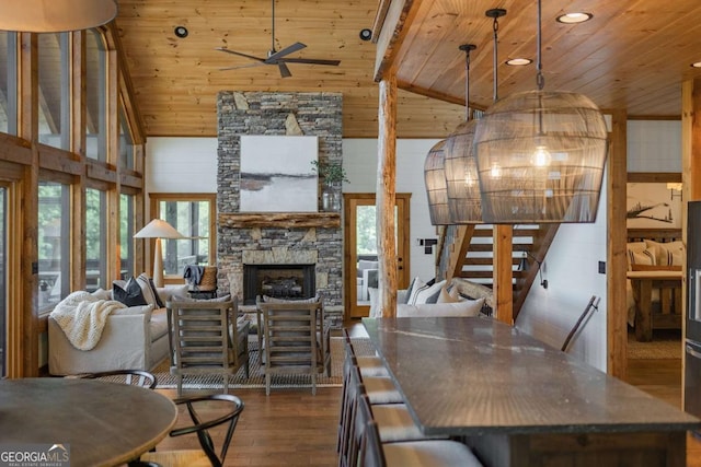 dining room featuring ceiling fan, dark wood-style flooring, wooden ceiling, and a fireplace