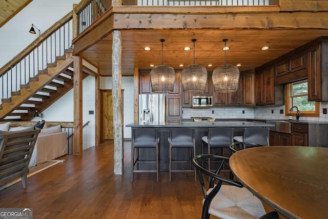 kitchen featuring wooden ceiling, a kitchen breakfast bar, dark wood-style flooring, stainless steel appliances, and a sink